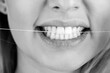 © Yevhen - Healthy teeth concept. Oral hygiene and health care. Smiling women use dental floss white healthy teeth. Dental flush - woman flossing teeth. Dental floss. Taking care of teeth. Black and white