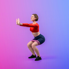 Wall Mural - Full body length gaiety shot athletic and sporty young woman with fitness elastic resistance band in squat exercise posture on isolated background. Healthy active and body care lifestyle.