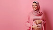 © ProstoSvet - Pregnant muslim lady in hijab embracing her big belly, smiling happy arabic woman standing over pink background and tenderly touching tummy, enjoying pregnancy time, copy space