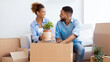 © Prostock-studio - Relocation. Cheerful Black Couple Packing Plant In Moving Box Sitting On Couch Indoor. Panorama