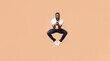 © Prostock-studio - A young Black man jumps in mid-air with a wide smile and open mouth, his arms bent at the elbows, as if holding something. He is wearing a white t-shirt and blue jeans
