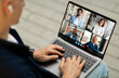 © Prostock-studio - A man sits at a desk and participates in a video conference meeting with four other people on his laptop. He is wearing a blue shirt and has his hand on the keyboard.