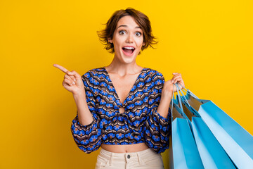 Wall Mural - Photo of person amazed girl demonstrate customers her discount coupon for every second piece clothes isolated on yellow color background
