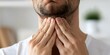 © Anastasiia - Man grimacing and holding his throat in discomfort, possibly due to a sore throat. Concept Sore Throat, Discomfort, Health Issue, Grimace, Pain