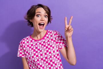 Wall Mural - Photo portrait of pretty young girl show v-sign excited impressed wear trendy pink outfit isolated on purple color background