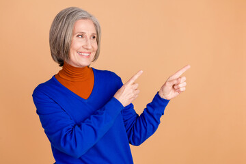 Canvas Print - Photo portrait of lovely pensioner lady look point empty space dressed stylish blue garment isolated on beige color background