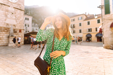 Wall Mural - Happy smiling woman wearing trendy summer outfit walking in street of European city. Fashion, lifestyle concept