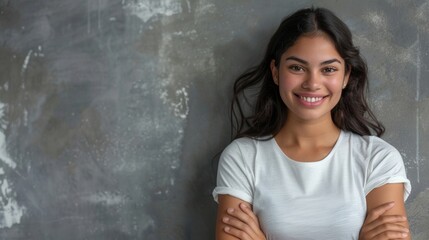 Wall Mural - A young Hispanic woman stands against a grey wall with her arms crossed and a pleasant smile. She is looking directly at the camera. Generative AI