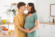 © Pixel-Shot - Young pregnant couple hugging in kitchen
