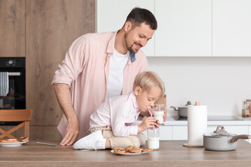 Poster - Little boy and his father with different pastries drinking milk in kitchen