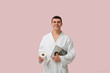 © Pixel-Shot - Portrait of handsome young man in bathrobe with magazine and toilet paper on pink background