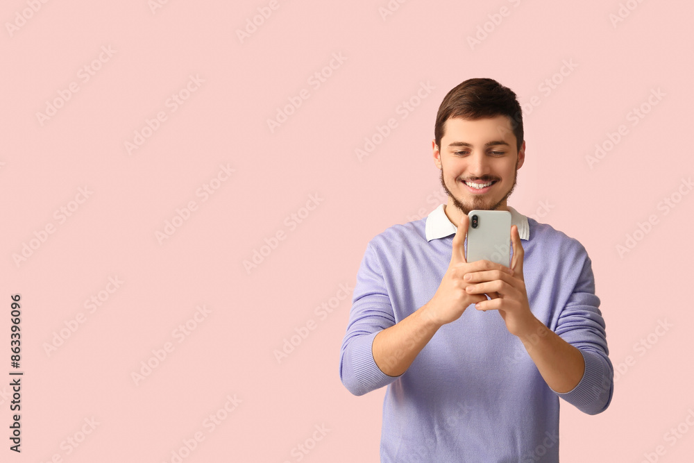Young man using mobile phone on pink background. Online dating concept