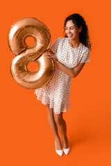 Wall Mural - Beautiful young African-American woman with air balloon in shape of figure 8 on orange background. International Women's Day