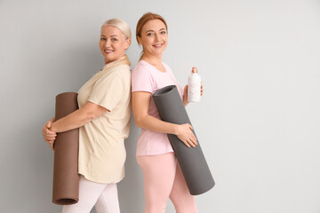 Sticker - Mature women with yoga mats and water bottle on light background