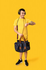 Sticker - Young man with sports bag and watch listening to music on yellow background