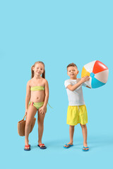 Wall Mural - Cute little children with wicker bag and beach ball on blue background