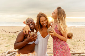 group of three female friends hugging and having a good time while enjoying a drink served in a coco