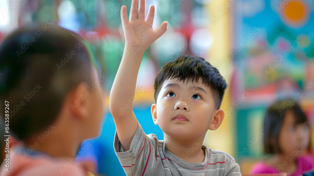 Young boy raising his hand eagerly in a colorful classroom setting ...