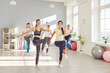 © Studio Romantic - Group of young sporty girls exercise, women stretching knee to elbow, warming up with coach, fitness club sportswomen group, happy team workout to improve flexibility. Active friends in sport together
