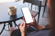 © Farknot Architect - Mockup image of a woman holding mobile phone with blank desktop screen in cafe