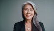 © Marko - Happy smiling stylish confident 50 years old Asian female professional standing looking at camera at gray background