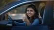 © Aamir - A happy young Indian woman sitting in a car and showing a thumbs up