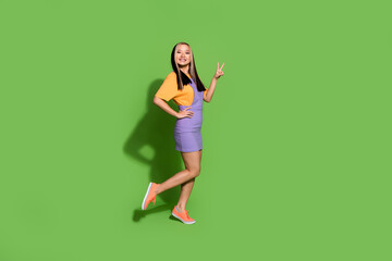 Wall Mural - Full length photo of lovely young lady v-sign show dressed stylish violet yellow garment isolated on green color background