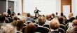 © kasto - Speaker giving a talk in conference hall at business event. Rear view of unrecognizable people in audience at the conference hall. Business and entrepreneurship concept