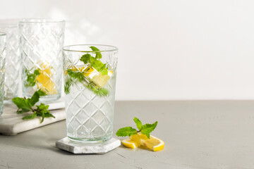 Wall Mural - A refreshing summer drink or alcoholic cocktail with ice, mint and lemon on a sunny day. A fresh healthy cold lemonade drink. Sparkling water with lemon