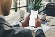 © ttonaorh - Mockup of a man's hands holding smart phone with blank white screen while sitting at the wooden table in modern office