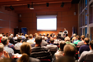 Wall Mural - Speaker giving a talk in conference hall at business meeting event. Rear view of unrecognizable people in audience at the conference hall. Business and entrepreneurship concept.