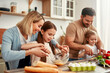 © Valerii Apetroaiei - The family is joyfully cooking together in a welllit kitchen using fresh ingredients