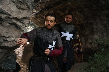 Two crusaders knights in armor with sword in castle ruins in Europe