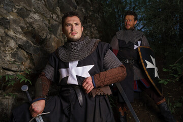 Two crusaders knights in armor with sword in castle ruins in Europe