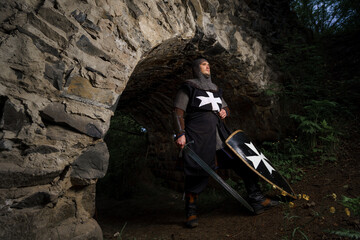 Crusader knight in armor with sword in castle ruins in Europe