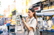 © twinsterphoto - Young Asian woman getting lost and using map on a mobile phone while traveling and backpacker in Khaosan Road outdoor market in Bangkok, Thailand