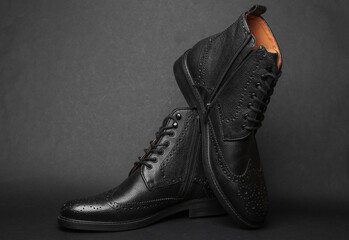 Wall Mural - Stylish black leather men's brogue boots on a black background