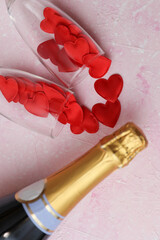 Wall Mural - Two glasses with red hearts, Champagne bottle on a pink concrete background