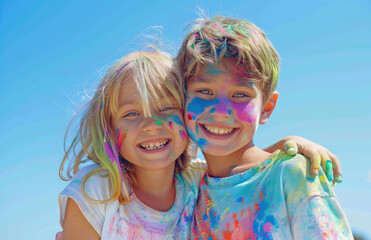 Wall Mural - two happy children with colorful paint on their faces, hugging and smiling at the camera against a blue sky.