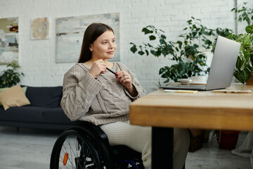 Wall Mural - A young woman in a wheelchair sits at a table in her home, pen in hand, reflecting on the day.