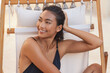 © puhhha - Face Skin Care. Young Woman Relaxing On Beach Chair With Wet Hair, Smiling And Enjoying Summer Sun. Concept Of Beach Relaxation, Haircare, And Natural Beauty.