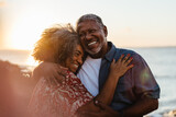 Elderly couple embracing at sunset, sharing joy and love by the seaside