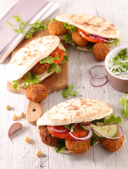 Poster - pita bread with falafel and vegetables on wood background