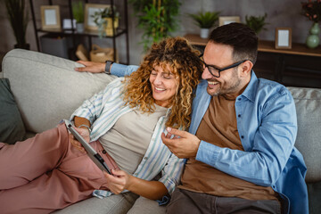 Wall Mural - Adult couple use tablet at home have fun together