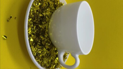 Wall Mural - A cup with gold glitter on a saucer is stirred with a spoon	