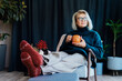 © okrasiuk - Middle aged woman relaxing with pumpkin shaped cup of hot drink in scandy style hygge interior home with fall mood decor. Lady dreaming, enjoy calm mood without stress, well being alone. Cozy autumn.