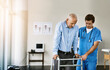 © Stratford/peopleimages.com - Physiotherapist, senior person and walking frame with help, balance or guide for steps in hospital. Doctor, elderly patient and men with mobility aid for recovery, rehabilitation or support at clinic