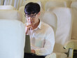 © panyajampatong - Businessman wearing casually dressed and using laptop computer while sitting on the airplane near windows. Business trip travel concept.