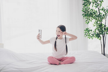 Poster - Full size photo of cute little girl smart phone make selfie show v-sign wear pajama comfy bed bedroom flat indoors