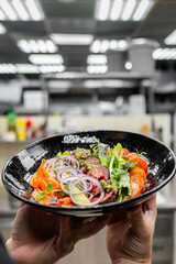 Wall Mural - Vibrant dish with meat, greens, and garnishes against a blurred kitchen background